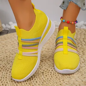 Nahaufnahme gelbe Strick-Sneaker mit Regenbogenbändern und Keilsohle für Damen