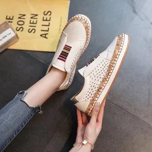 Détail de mocassins blancs perforés avec une bande élastique à rayures colorées