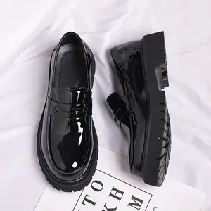 Detailweergave van zwarte lakleren loafers met dikke platformzolen.