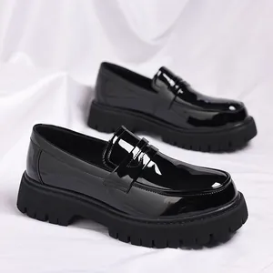 Detailopname van glanzende zwarte herenloafers met dikke plateauzool en ronde neus van leer