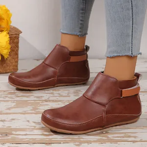 Détail de bottines en similicuir marron avec sangle décorative et semelle plate