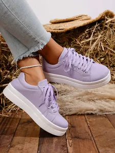 Zapatillas de lona lavanda con suela de plataforma blanca gruesa usadas por una modelo.