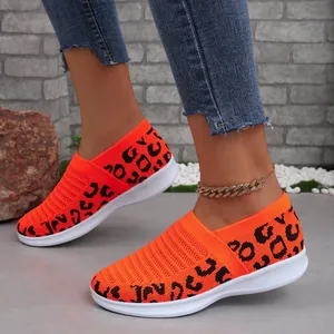 Gedetailleerd overzicht van de feloranje gebreide sneakers met luipaardprint op voet