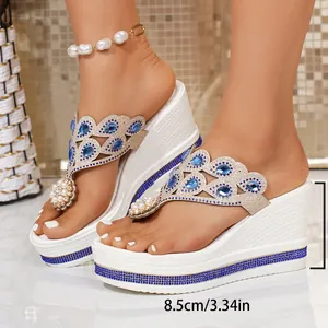 Detailed view of white wedge flip-flops with 8.5cm platform and blue rhinestones