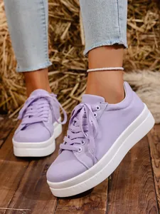Detalle de zapatillas de plataforma de lona violeta con cordones y suela blanca gruesa.