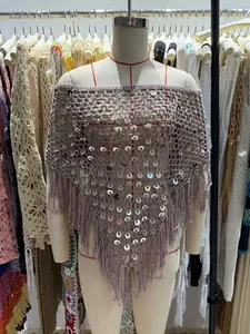 Dettaglio di uno scialle triangolare all'uncinetto con paillettes e nappe su manichino.