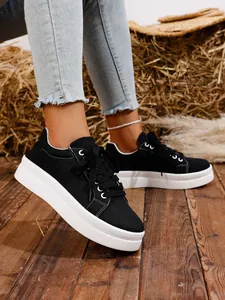 Primer plano de zapatillas de plataforma de lona negra con costuras blancas y suelas.