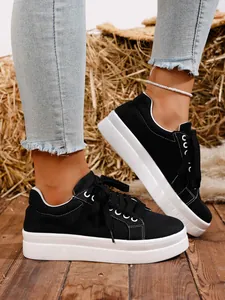 Vista de detalle de zapatillas de lona negra con plataforma, cordones y suela blanca.