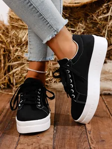 Primer plano de zapatillas de plataforma de lona negra con suela blanca en suelo de madera