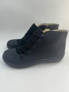 Side view of retro black flat ankle boots with elastic lace details and side zipper