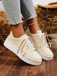 Vista lateral de zapatillas de lona beige para mujer con suela gruesa y cordones blancos.