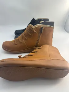 Detailed macro view of vintage style flat ankle boots showing textured sole and side zipper.