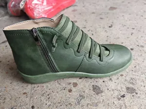Detailed side view of a vintage green faux leather flat short boot with side zipper