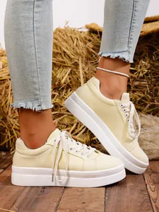 Primer plano de zapatillas de lona con plataforma amarillas para mujer y cordones