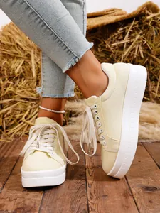 Primer plano de zapatillas de lona amarillas con plataforma blanca sobre suelo de madera