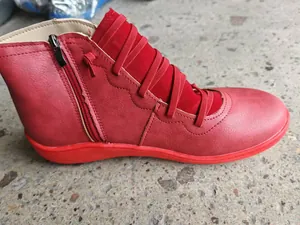 Detail view of a red retro women's ankle boot with elastic straps and side zipper.