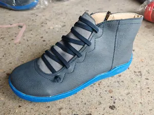 Detail view showing the wave-patterned stitching and elastic straps on blue leather boots