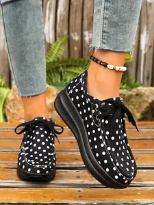 Detailopname van zwart-witte polkadot platform schoenen gedragen op een houten terras