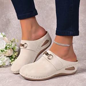Detailed view of beige platform mules featuring golden chain buckle and stitched detailing
