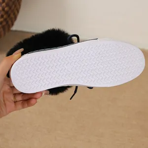 Close-up view of white wavy non-slip rubber sole on black plush winter snow boots