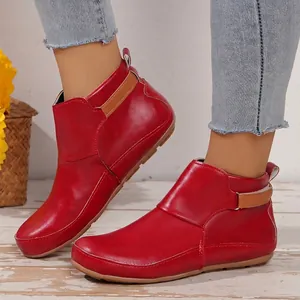 Détail en gros plan de bottines plates en cuir rouge avec une bride velcro élégante aux pieds