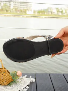 Detailed view of the non-slip black rubber sole on a paisley print flat sandal