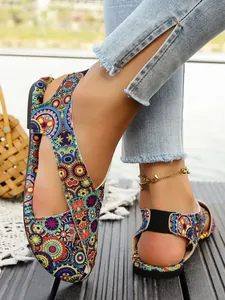 Close-up detail of bohemian flat sandals with colorful ethnic pattern and blue denim jeans