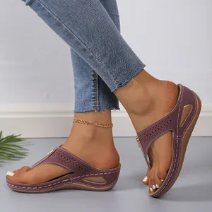 Nahaufnahme lila Keilabsatz-Flip-Flops mit lasergeschnittenen Details und weißen Nähten