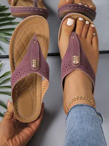 Makroansicht von lila Zehensandalen mit Laser-Cut-Mustern und goldenen Metallschnallen.