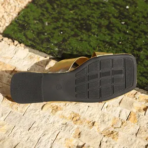 Detailed macro view of the non-slip black rubber sole on a gold square-toe sandal.
