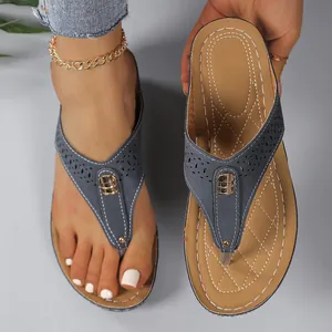 Detaillierte Makroansicht grauer Keil-Flip-Flops mit gestepptem Fußbett und Goldschnalle