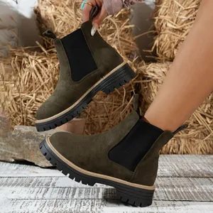 Botines Chelsea de ante verde oscuro con suela gruesa de tacos en un entorno rústico