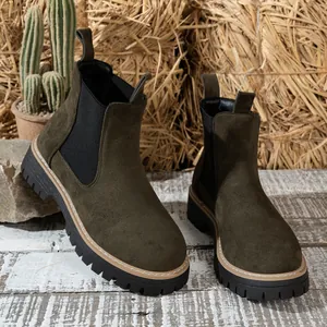 Botines Chelsea de ante verde oliva con suela gruesa en un ambiente rústico campestre