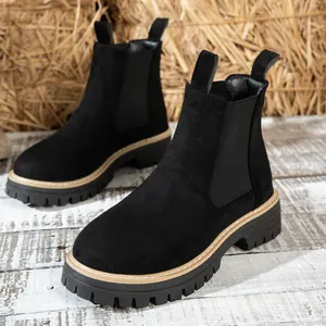 Vista detallada de botas Chelsea de ante negro con suelas de plataforma, estilo rústico