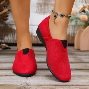 Detailed view of red suede wedge loafers with V-shaped elastic and black soles
