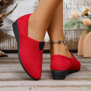 Close-up of red suede pointed-toe wedge slip-on shoes for women in a rustic setting
