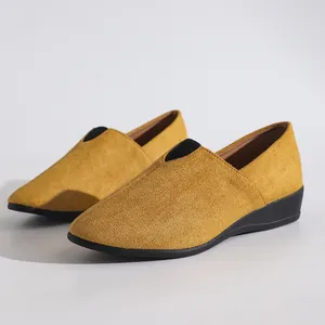 Detailed view of yellow suede wedge slip-on shoes with pointed toe and black elastic