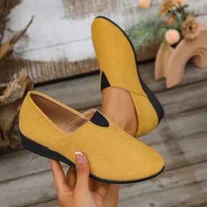Detailed close-up of yellow suede wedge loafers featuring a black elastic slip-on design