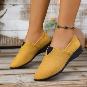 Close-up of women's yellow suede wedge loafers with pointed toe and slip-on design