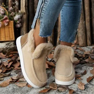 Primer plano de botas de nieve beige cálidas con forro grueso de piel sintética de invierno.