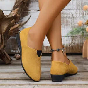 Detailed close-up view of elegant yellow suede wedge shoes with pointed toe on model.