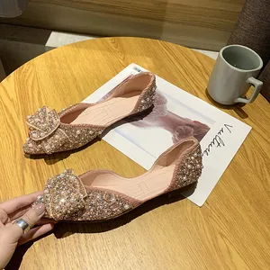 Detailweergave van champagne ballerina's met puntige neus en strik van strass en parels