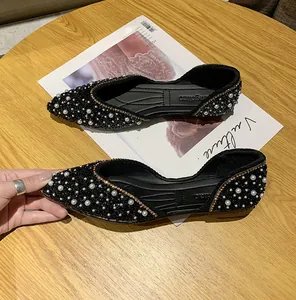 Gedetailleerde close-up van zwarte puntige ballerina's met parel- en strass-details.
