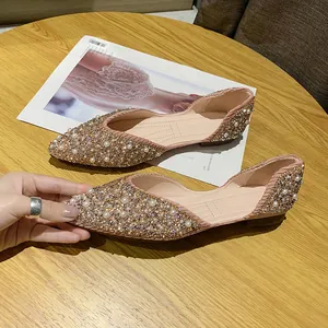 Detailopname van puntige platte schoenen met strass-steentjes en parelversieringen