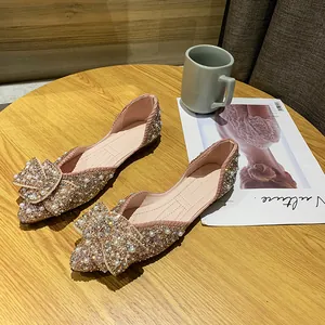 Elegante roze spitse ballerina's met strass en parelmoer strik op een houten tafel.