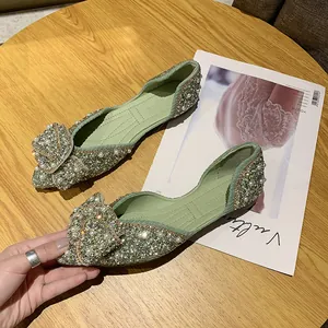 Detailopname van groene puntige platte schoenen met sprankelende stras- en parelstrik.