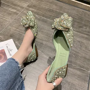 Detailopname van groene puntige platte schoenen met een strik van parels en strass