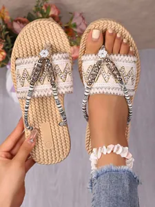 Detail der flachen Bohemian-Sandalen mit gewebter Textur und ethnischen Metallanhängern