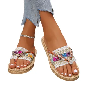 Modische böhmische flache Flip-Flops mit bunten ethnischen Mustern und Blumenanhängern
