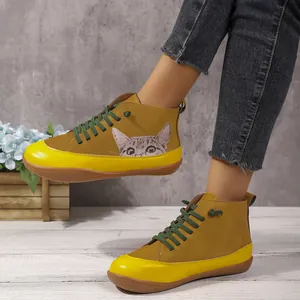 Gedetailleerde weergave van gele hoge platte schoenen met kattenillustratie en groene veters.